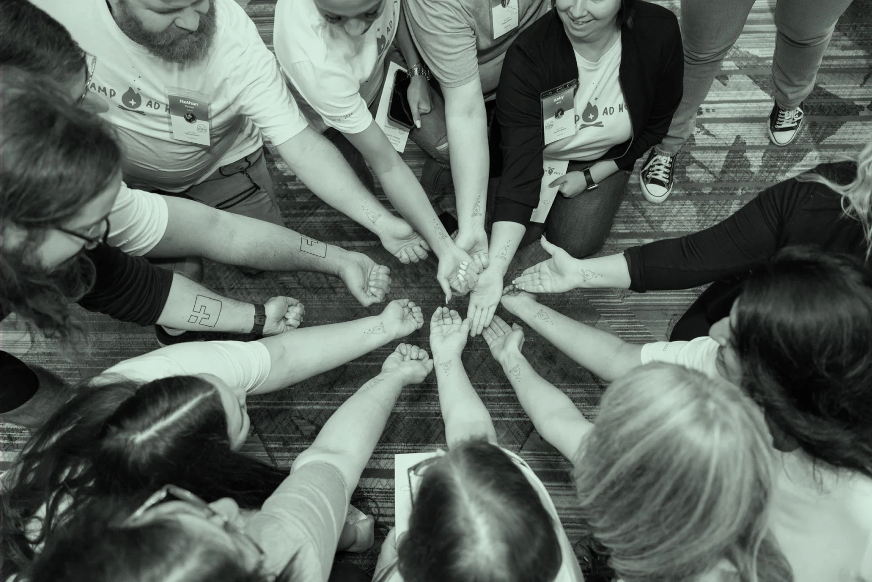 An image showing Ad Hoc team members, with temporary Ad Hoc Tattos - their arms are together forming a circle, with hands in the middle.